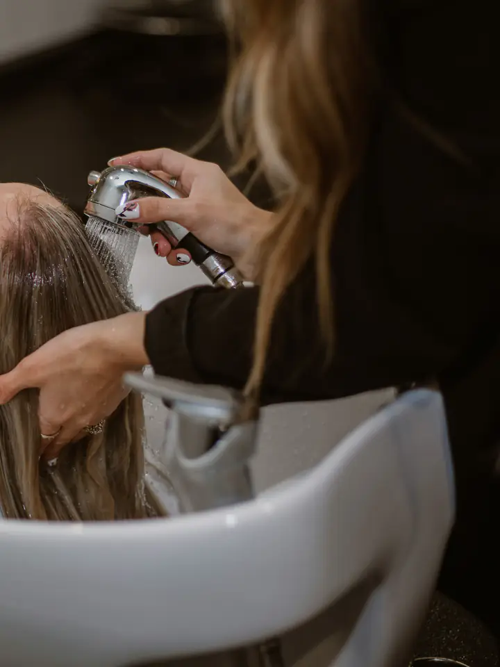 Un shampoing au bac, la main de la coiffeuse dans les cheveux