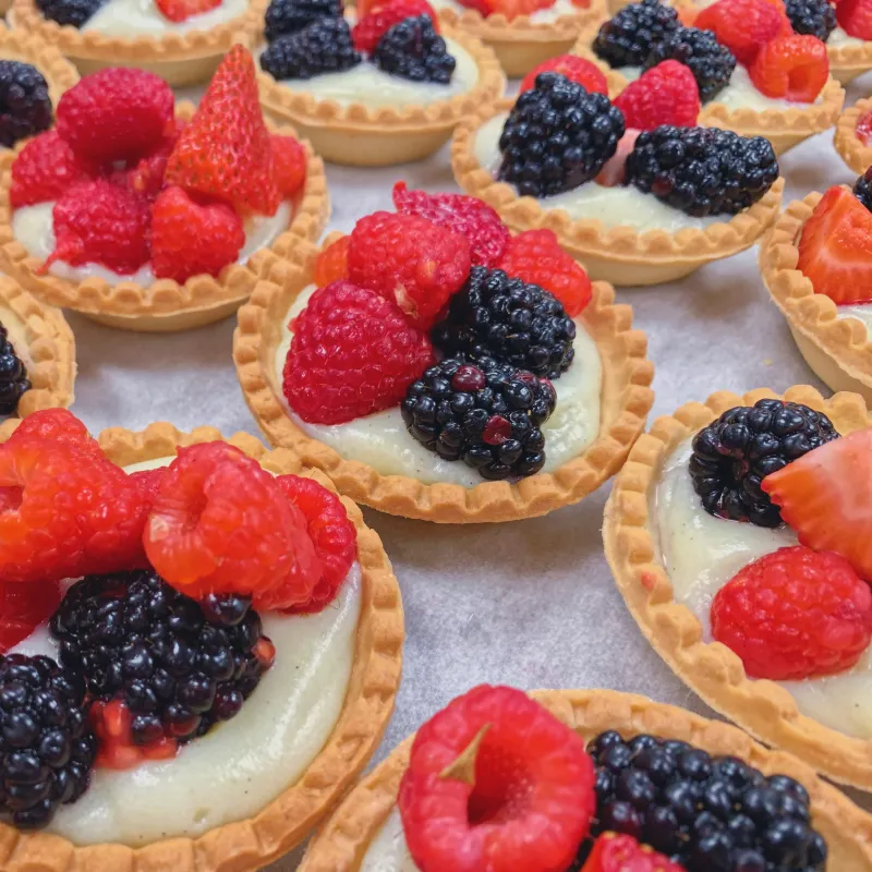 Des tartelettes de framboises, de mûres et de fraises sur crème pâtissière