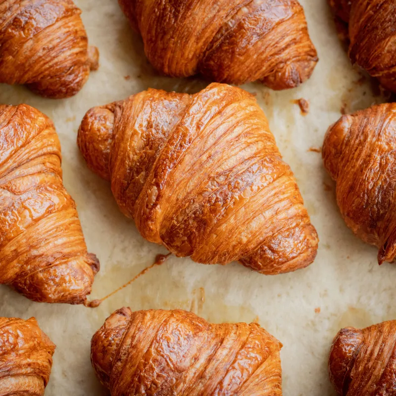 Des croissants dorés alignés sur une plaque, à la sortie du four