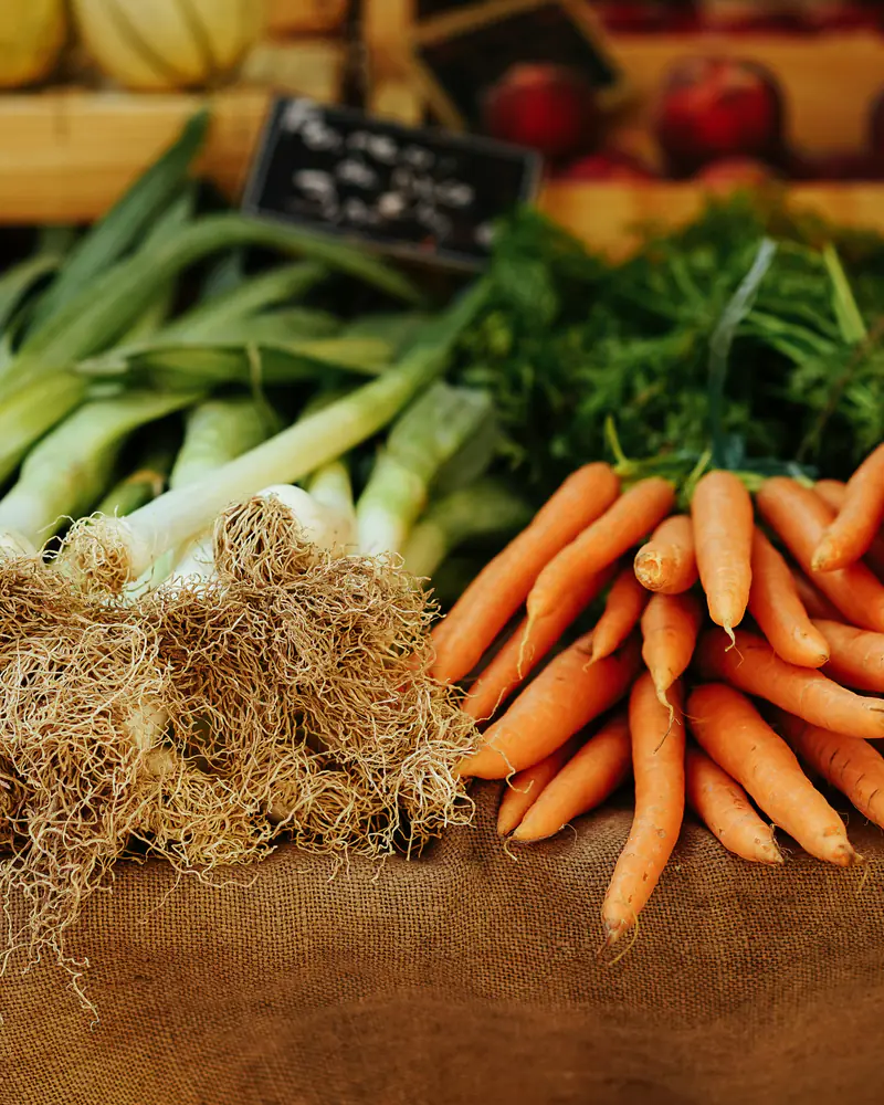 Poireaux et carottes en bottes sur un étal de marché